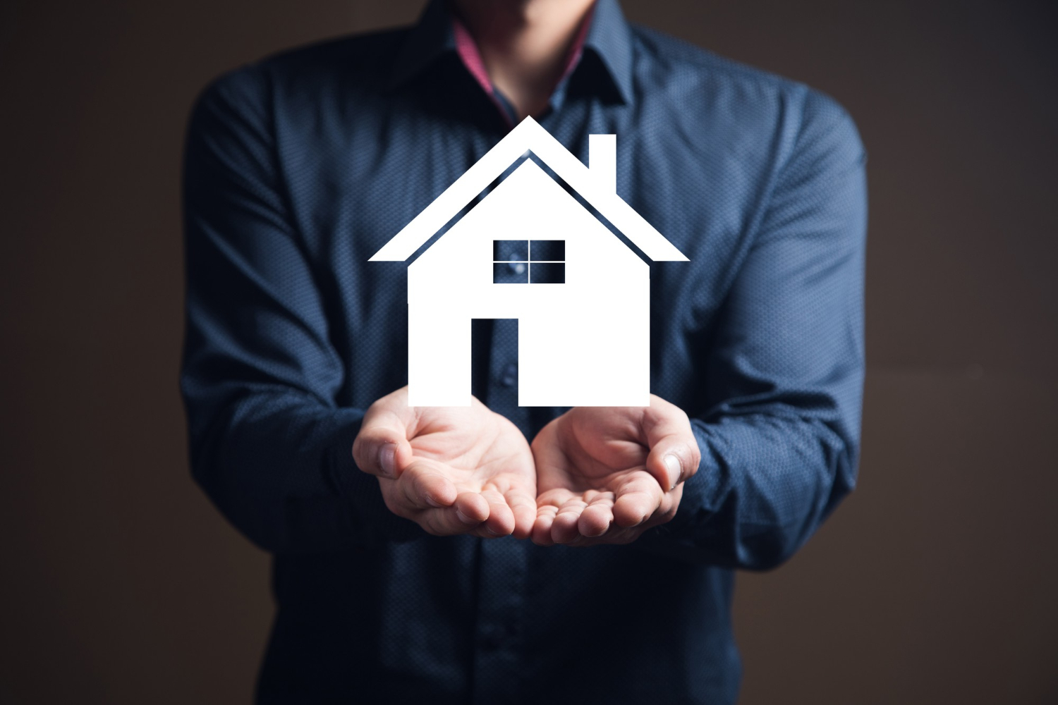 un homme tient entre ses mains une maison blanche